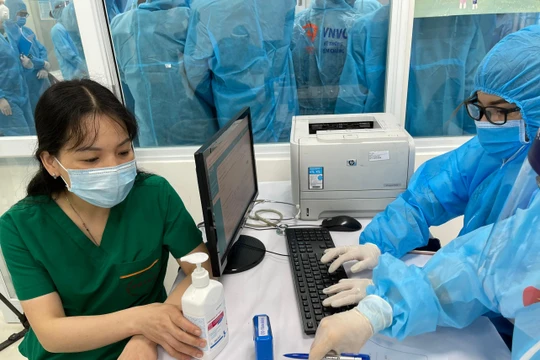 Nhân viên y tế kiểm tra hồ sơ, chuẩn bị tiêm vacicne phòng COVID-19 (Ảnh - Tuấn Dũng) 