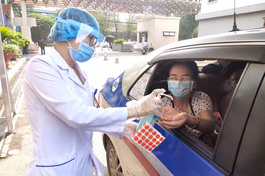 Nhân viên y tế hỗ trợ rửa tay cho người dân trước khi vào bệnh viện (Ảnh - Minh Thuý) 