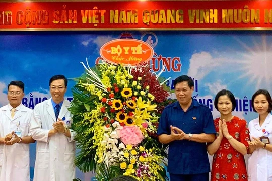 Thứ trưởng Bộ Y tế Đỗ Xuân Tuyên (áo xanh) chúc mừng em bé đầu tiên ra đời bằng kỹ thuật thụ tinh trong ống nghiệm. (Ảnh: Thảo Nguyên)