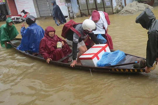 Người dân di chuyển khi nước lũ dâng cao (Ảnh: Hoàng Triều - Nguồn: baothuathienhue.vn)