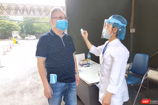 Nhân viên y tế đo nhiệt độ cho người dân trước khi vào Bệnh viện