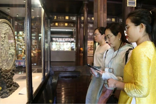 Du khách sử dụng smartphone với chip NFC gắn trên cổ vật trưng tại Cung đình Huế.