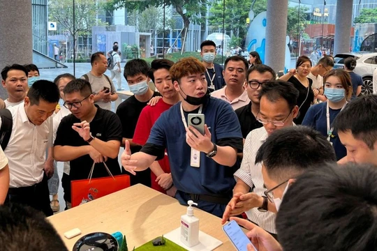 Một nhân viên giới thiệu điện thoại thông minh Huawei Mate 60 tới khách hàng tại cửa hàng của Huawei ở Thâm Quyến (ảnh: Reuters)