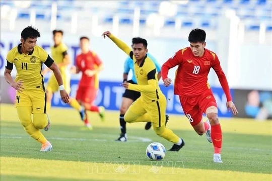 Tiền đạo Nhâm Mạnh Dũng đi bóng qua cầu thủ Malaysia