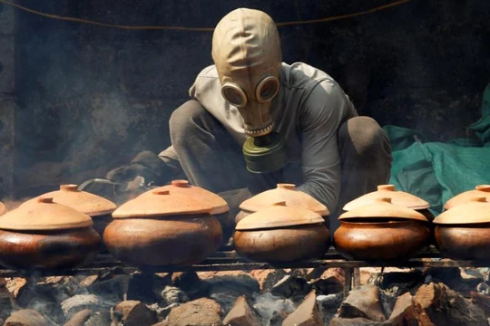 Anh Bùi Văn Cường đeo mặt nạ phòng độc để kho cá trắm (ảnh: Reuters)