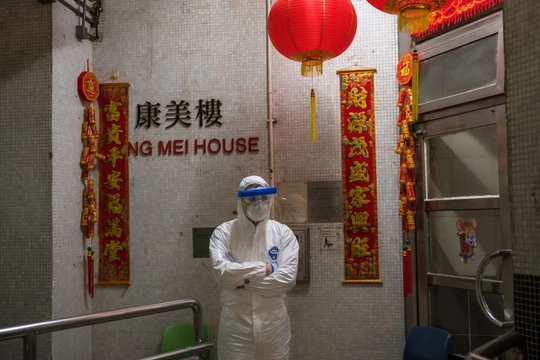 Một nhân viên y tế mặc đồ bảo hộ đứng bảo vệ bên ngoài lối vào tòa nhà chung cư ở Tsing Yi (Hồng Kông) sau khi phát hiện cư dân thứ hai nhiễm virus tại đây. Hơn 100 người sống tại tòa chung cư này đã được sơ tán (ảnh Getty Images)