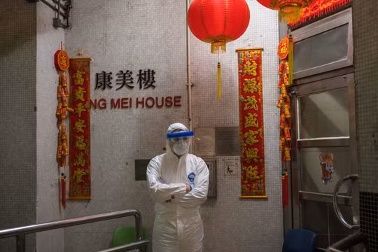 Một nhân viên y tế mặc đồ bảo hộ đứng bảo vệ bên ngoài lối vào tòa nhà chung cư ở Tsing Yi (Hồng Kông) sau khi phát hiện cư dân thứ hai nhiễm virus tại đây. Hơn 100 người sống tại tòa chung cư này đã được sơ tán (ảnh Getty Images)