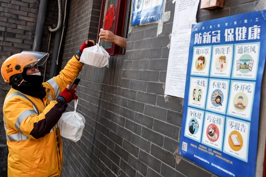 Một lái xe công nghệ nhận đồ ăn qua cửa sổ từ một nhà hàng ở Bắc Kinh