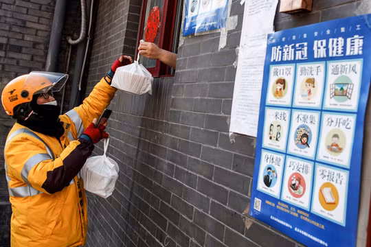 Một lái xe công nghệ nhận đồ ăn qua cửa sổ từ một nhà hàng ở Bắc Kinh