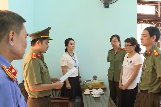 Bà Nguyễn Thị Hồng Nga, chuyên viên Phòng khảo thí và quản lý chất lượng Sở GD-ĐT Sơn La (mặc áo trắng bên phải), nghe tống đạt quyết định khởi tố bị can. 