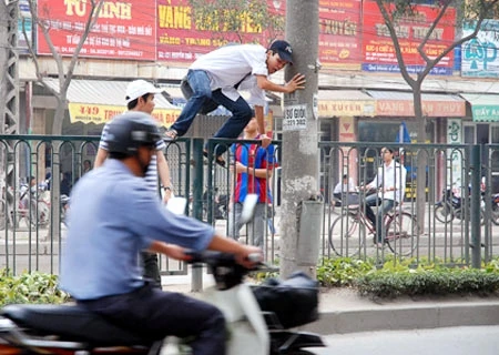 Người đi bộ trèo qua rào chắn giữa đường (Ảnh: VnExpress)