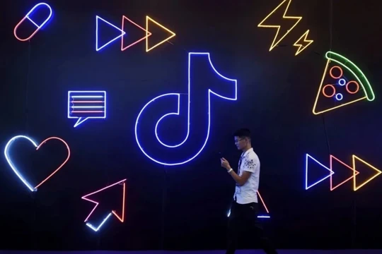 Một người đàn ông cầm điện thoại đi ngang qua biển hiệu có logo ứng dụng Douyin của ByteDance tại Hàng Châu, tỉnh Chiết Giang, Trung Quốc. (Ảnh:SCMP)