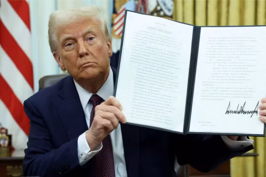 Tổng thống Mỹ Donald Trump cầm một sắc lệnh hành pháp đã ký về tiền điện tử. Ảnh: Reuters.