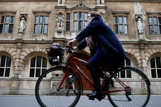 Một người phụ nữ đi xe đạp bên cạnh trường Oriel College ở Oxford, Anh (ảnh: Thomson Reuters)