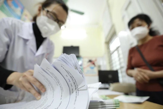 Giấy chứng nhận khỏi bệnh được trạm y tế phường thông báo cho tổ trưởng tổ dân phố đến nhận và phát cho các bệnh nhân F0 khỏi bệnh. (Ảnh: Minh Quyết/TTXVN)