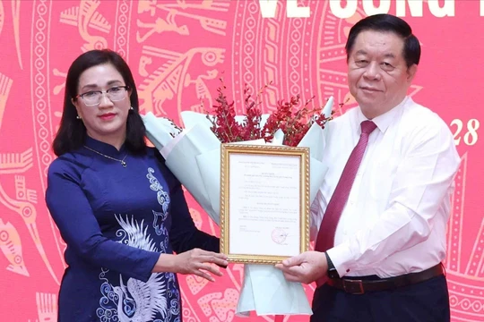 Trưởng Ban Tuyên giáo Trung ương Nguyễn Trọng Nghĩa trao quyết định cho bà Đinh Thị Mai. Ảnh: TTXVN