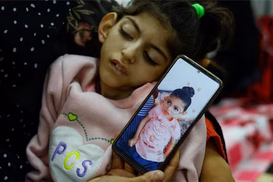 Umm Mesbah Heji ôm cô con gái suy dinh dưỡng Israa, bị liệt tứ chi và động kinh tại trung tâm y tế al-Awda ở Rafah, ngày 12/3 (Ảnh: Reuters)