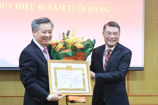 Trưởng Ban Tổ chức Trung ương Lê Minh Hưng trao Huy hiệu 40 năm tuổi Đảng cho ông Nguyễn Quang Dương (trái).