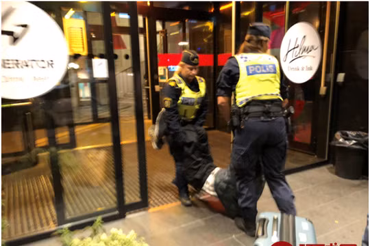 Bức ảnh được đăng trên báo chí Trung Quốc cho thấy cảnh sát Thụy Điển đang khiêng du khách ra khỏi khách sạn đưa lên xe