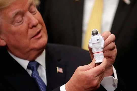 Tổng thống Mỹ Donald Trump cầm bức tượng đồ chơi một nhà du hành vũ trụ ở Nhà Trắng (Ảnh Reuters)