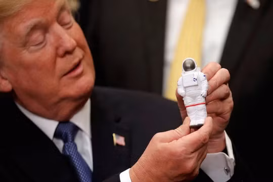 Tổng thống Mỹ Donald Trump cầm bức tượng đồ chơi một nhà du hành vũ trụ ở Nhà Trắng (Ảnh Reuters)