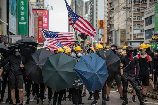 Người biểu tình mang theo cờ Mỹ khi tuần hành ở quận Yuen Long hôm 27/7 (Ảnh: CNN)