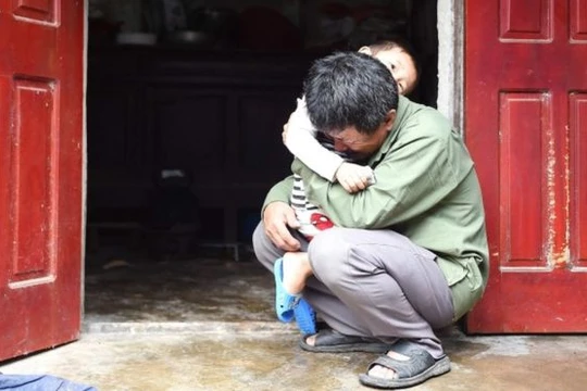 ông Lê Văn Tuấn ôm đứa cháu trai, bật khóc khi không có tin tức gì về người con trai Lê Văn Hà (ảnh: Getty Images)