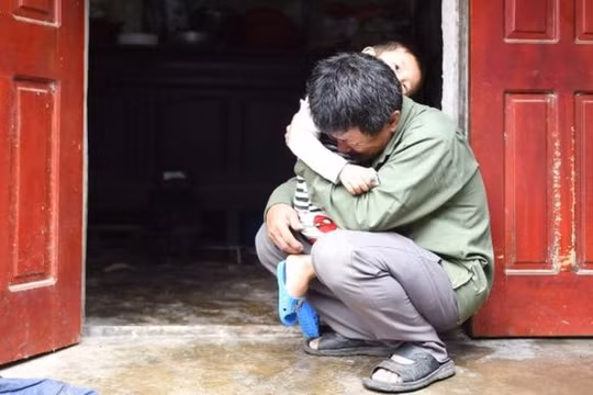 ông Lê Văn Tuấn ôm đứa cháu trai, bật khóc khi không có tin tức gì về người con trai Lê Văn Hà (ảnh: Getty Images)