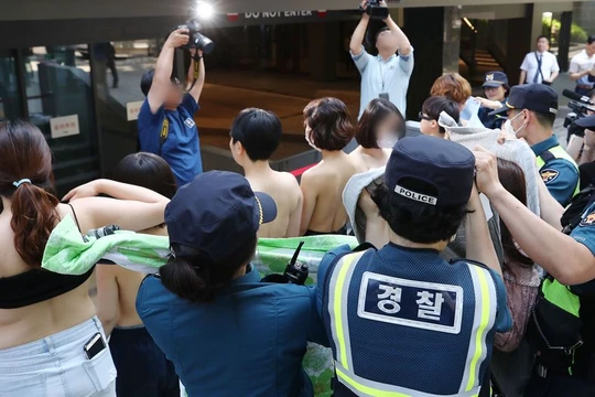 Ngay khi các phóng viên xuất hiện, những người phụ nữ đã cởi áo ngoài để truyền tải thông điệp: "Cơ thể chúng tôi không phải tài liệu khiêu dâm" (ảnh: Yonhap)