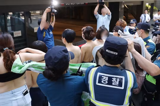 Ngay khi các phóng viên xuất hiện, những người phụ nữ đã cởi áo ngoài để truyền tải thông điệp: "Cơ thể chúng tôi không phải tài liệu khiêu dâm" (ảnh: Yonhap)