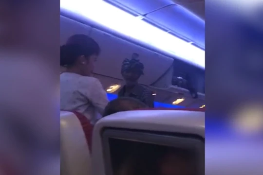 Một người đàn ông cầm túi nhựa đi xin tiền hành khách trên chuyến bay của hãng Qatar Airways (ảnh cắt từ clip)