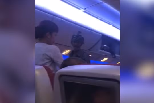 Một người đàn ông cầm túi nhựa đi xin tiền hành khách trên chuyến bay của hãng Qatar Airways (ảnh cắt từ clip)