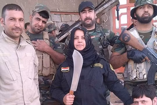 "Bà nội trợ" Wahida Mohamed Al-Jumaily đứng bên các chiến binh dưới quyền. (Nguồn: Independent).