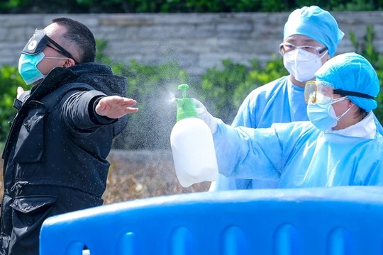 Nhân viên y tế ở Vũ Hán khử trùng bệnh nhân trước khi ra viện.(Ảnh Đông Phương).