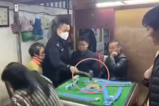 Người cảnh sát giận dữ dùng búa đập phá bàn mạt chược (Ảnh: Đông Phương)