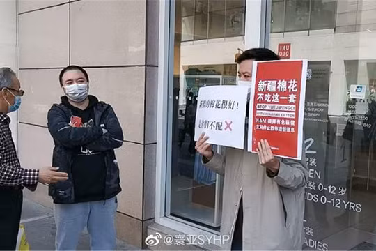 Một người mang biểu ngữ tẩy chay H&M đứng chắn trước một cửa hàng của thương hiệu này ở Hồ Nam (Ảnh: Đa Chiều).