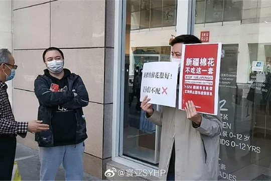 Một người mang biểu ngữ tẩy chay H&M đứng chắn trước một cửa hàng của thương hiệu này ở Hồ Nam (Ảnh: Đa Chiều).