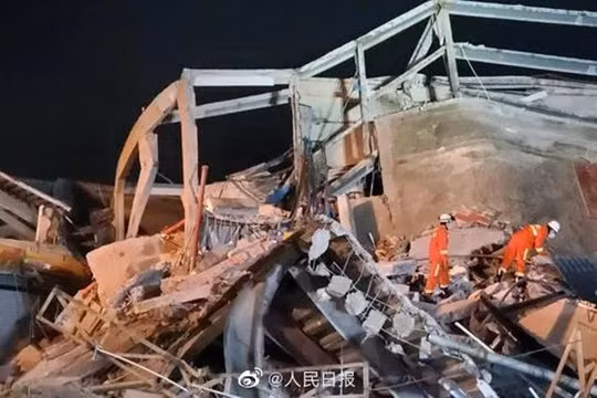 Các nhân viên cứu hộ tìm kiếm nạn nhân trong đống đổ nát (Ảnh: Nhân dân Nhật báo).