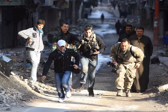 Các nhà báo mạo hiểm băng qua một con đường trong thành phố đang có chiến sự Aleppo ở Syria năm 2012 - Ảnh: Reuters