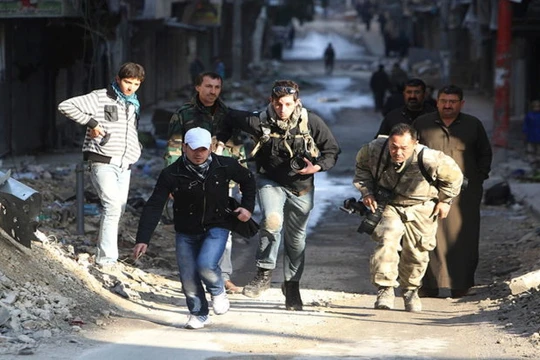 Các nhà báo mạo hiểm băng qua một con đường trong thành phố đang có chiến sự Aleppo ở Syria năm 2012 - Ảnh: Reuters