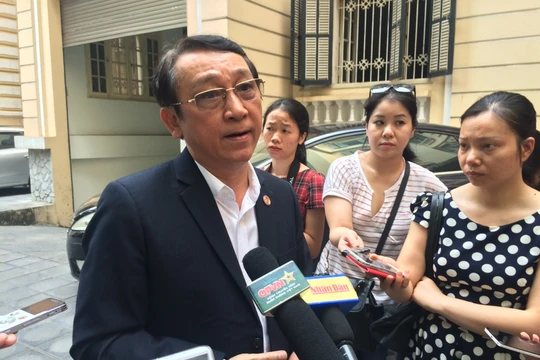 Ông Huỳnh Tấn Vinh trao đổi với cơ quan báo chí bên ngoài hành lang buổi tọa đàm. Ảnh - Quang Vững