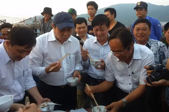 Chủ tịch UBND TP Đà Nẵng (đội mũ) ăn cá tại cảng cá Thọ Quang để dân an tâm - Ảnh: Đoàn Cường