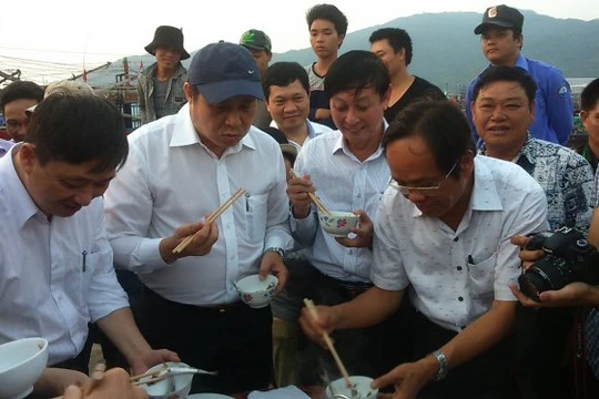 Chủ tịch UBND TP Đà Nẵng (đội mũ) ăn cá tại cảng cá Thọ Quang để dân an tâm - Ảnh: Đoàn Cường