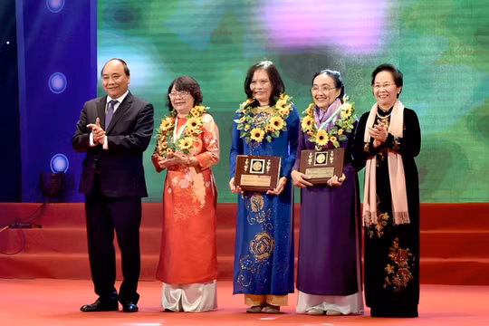 Thủ tướng Nguyễn Xuân Phúc (trái) và Nguyên Phó Chủ tịch nước Nguyễn Thị Doan (phải) tặng hoa cho các phụ nữ điển hình tiên tiến.