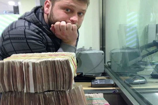 Hacker Seleznev với những cọc tiền bên cạnh chiếc máy tính xách tay của anh này vào thời điểm bị bắt tại Maldives năm 2014 - Ảnh: Bộ Tư pháp Mỹ