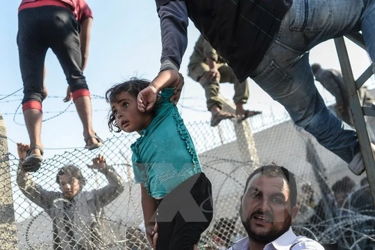 Người tị nạn Syria vượt qua hàng rào dây thép gai tại biên giới Thổ Nhĩ Kỳ. 