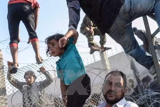 Người tị nạn Syria vượt qua hàng rào dây thép gai tại biên giới Thổ Nhĩ Kỳ. 