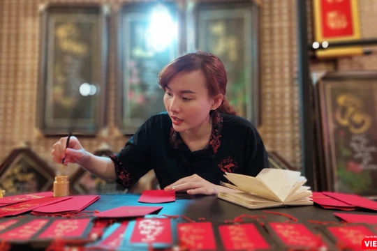 Một nữ thư pháp gia còn rất trẻ đang cho chữ tại phố ông đồ trước Nhà văn hóa Thanh niên 