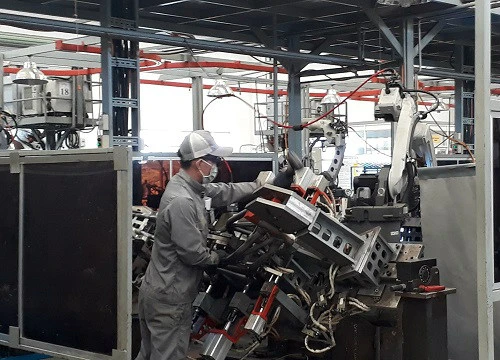 Công nhân Công ty VPIC thực hiện ráp phần khung sườn chiếc xe máy Ducati lên khuôn, các việc còn lại sẽ do robot thực hiện. Mỗi công nhân sẽ phụ trách 2 robot. Ảnh: Hà Thế An.