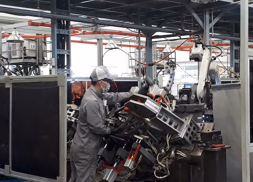 Công nhân Công ty VPIC thực hiện ráp phần khung sườn chiếc xe máy Ducati lên khuôn, các việc còn lại sẽ do robot thực hiện. Mỗi công nhân sẽ phụ trách 2 robot. Ảnh: Hà Thế An.